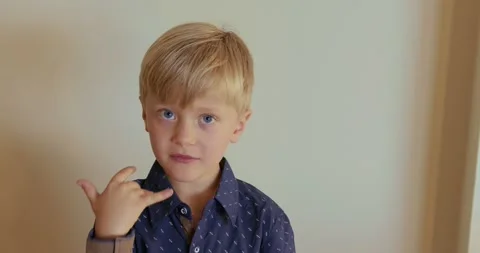 A 6-year-old boy in a blue shirt is licking his fingers after a sweet donut. Video stock 320640933
