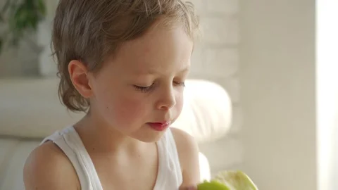 6 year old boy eating green apple and try pull out baby teeth Vídeos de archivo 107932661