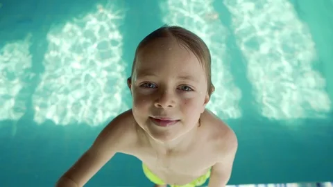 6 year old boy falling into the pool with blue water. Splashes fly in different Stock Footage 106072935