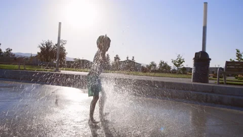 6 year old boy joyfully dances in splash pad water jet in slow motion Stock Footage 233942148
