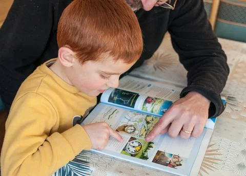 6-year-old boy studies with the help of his father Stock Photos