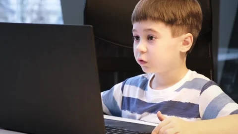 6 year old boy using laptop. Concentrated child solves difficult task. Uses Vidéo 263664310