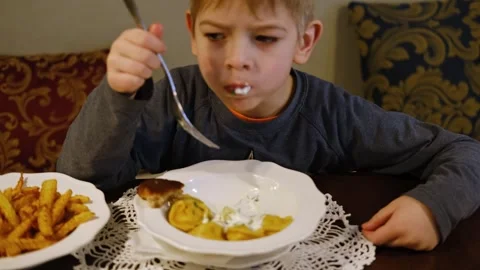 6 Years Old Boy has a Dinner in a Restaurant. Child is eating dumplings. Lunch Stock Footage 306162728