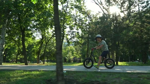 6 years old boy riding a runbike in a park Stock Footage 134982216