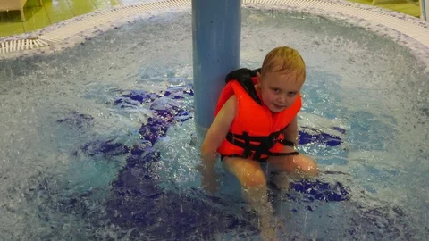6 years old boy sitting in the paddling pool.Top small rivulets pouring water. 스톡 동영상 122994829