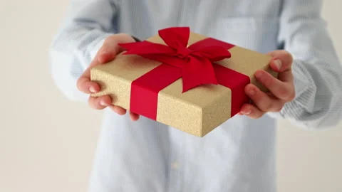 60 fps 4K video of hands of young boy giving present box with red bow Video stock 164019436