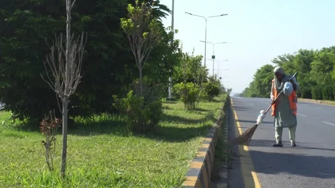 60 years old female Worker cleaning street with broom tool. Street sweeper Stock Footage 245820693