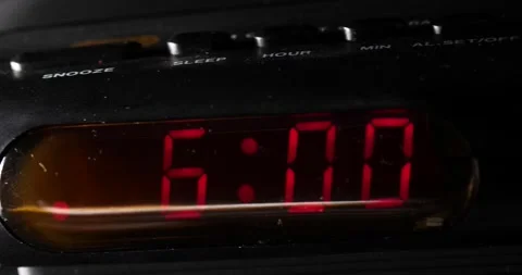 6:00 a.m. Black clock sitting on side of bed slow pan left Stock Footage 204059752