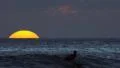 60p Slow motion surfer with big setting sun disk in UHD 4k or 4k+ Resolution