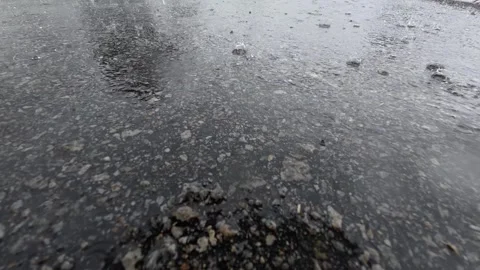 65 Close up of raindrops falling and splashing on wet asphalt pavement Stock Footage 345461134
