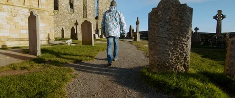 6K - Man Walking Through a Castle Cemetery Stock Footage 123372097