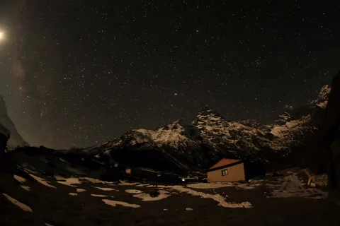 6K. Time lapse of the night sky with clouds and stars passing by behind mountain Stock Footage 41797698