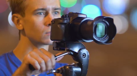 7 in 1 video! Man shoot with camera by bright lights background Stock Footage 53476805