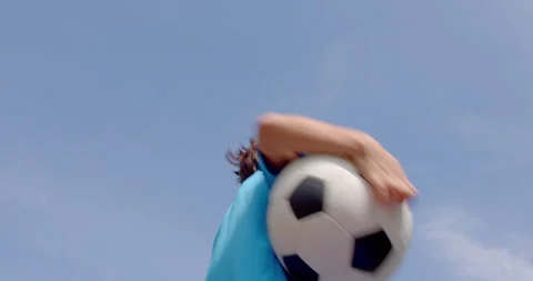 A 7-8 years old boy in football equipment and a ball in hand having fun jumping Stock Footage 161952536
