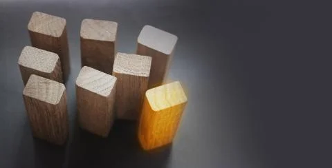 7 same and 1 different wooden blocks standing on black background. Leadership Stock Photos