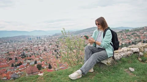 7 A woman using a phone while sitting on the hill with a beautiful top view Stock Footage 241781200