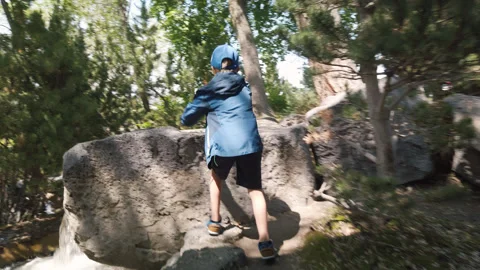 7 year old boy climbs over large boulder in city park, slow motion Stock-Footage 248325969