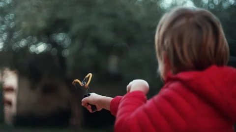 7 year old boy enjoys playing with the slingshot outdoors Stock Footage 262347951