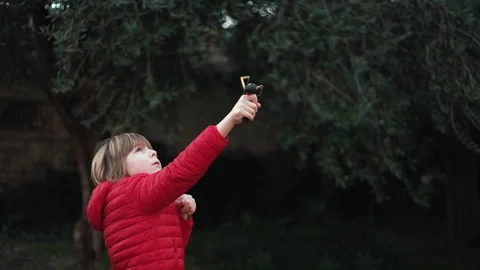 7 year old boy enjoys playing with the slingshot outdoors Stock Footage 262348802