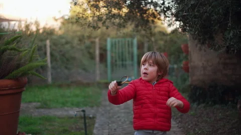 7 year old boy enjoys playing with the slingshot outdoors Stock Footage 262349259