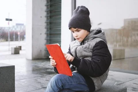 7 year old boy playing online game on tablet computer outdoors in winter Stock Photos