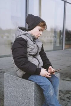 7 year old boy playing with smartphone outdoors in winter Foto stock