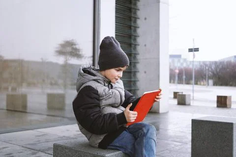 7 year old boy playing online game on tablet computer outdoors in winter Stock Photos