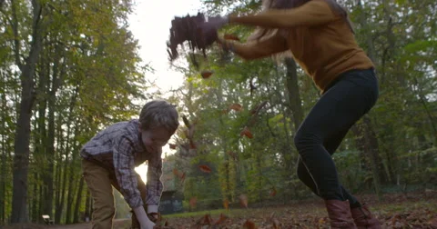 7 year old boy throwing leafs up with his mum falltime Stock Footage 53262877
