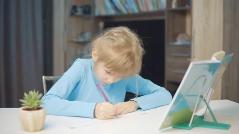 7 year old girl doing homework with textbooks Stock Footage 148257576