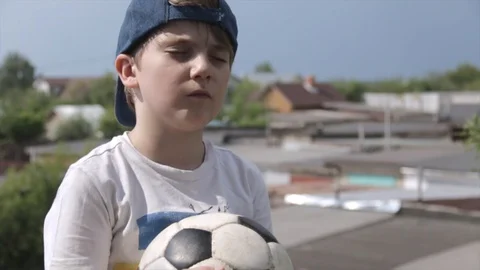 7 year-old Russian white boy in cap with closed eyes and a soccer ball in his Stock Footage 91214636