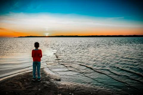 7 years old boy watching the sunrise on a summer day Stock Photos