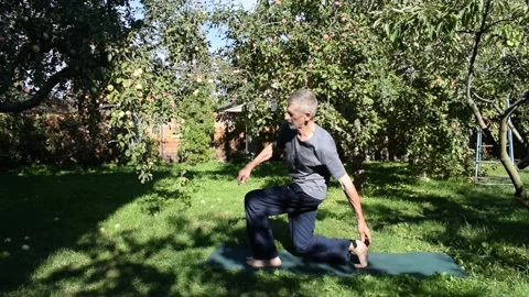 A 76-year-old man performs a physical exercise to strengthen his leg muscles. Stock Footage 317638705