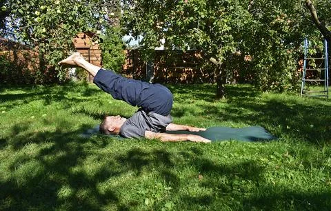 A 76-year-old man performs exercises to strengthen his abdominal and back m.. Stock Photos