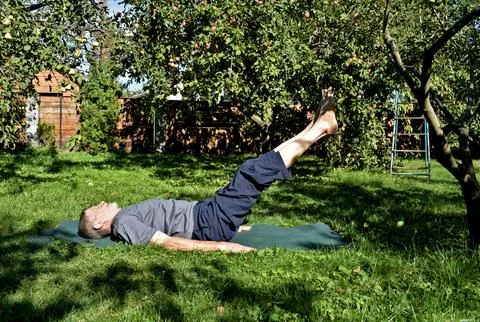 A 76-year-old man performs exercises to strengthen his abdominal and back m.. 스톡 사진