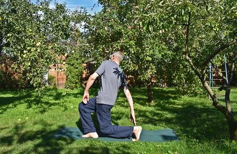 A 76-year-old man performs exercises to strengthen his leg muscles in the g.. Stock Photos