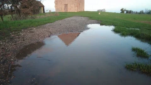 A 7th Century Chapels reflection is seen in a puddle before being revealed 4k Stock Footage 223202736