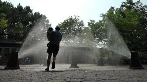 8-11-26, Brooklyn, NY, USA - slomo summer man carries child through sprinklers Stock Footage 341898582