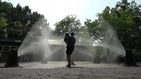 8-11-26, Brooklyn, NY, USA - slomo summer man carries child through sprinklers Stock Footage 341898702