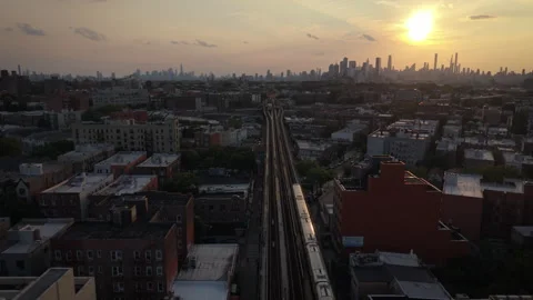 8-15-26, Queens, NY, USA - wider sunset aerial shot of train headed for NYC Stock Footage 342304777