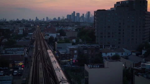 8-15-26, Queens, NY, USA - sunset aerial shot of elevated train headed for NYC Stock Footage 342304805