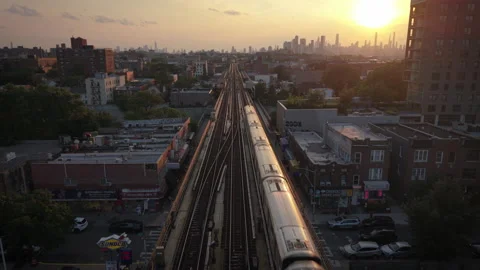 8-15-26, Queens, NY, USA - sunset aerial shot of elevated train bound for NYC Stock Footage 342306123