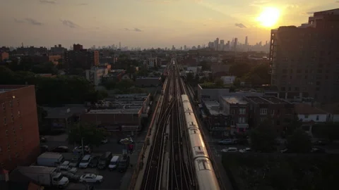 8-15-26, Queens, NY, USA - wider sunset aerial shot of train bound for NYC Stock Footage 342306754