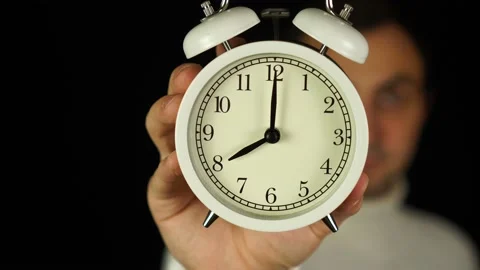 8 o'clock. Human hand holding alarm clock that showing eight o'clock and ringing Stock Footage 143378792