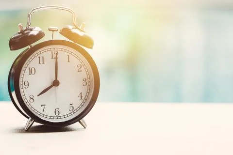 8 o'clock retro clock at white desk near swimming pool Stock Photos