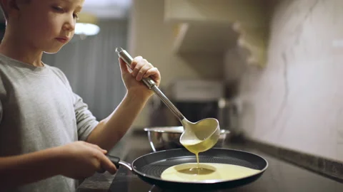 8 year-old boy cooks in the kitchen. Child pours the mixture for frying panca Stock Footage 142344706