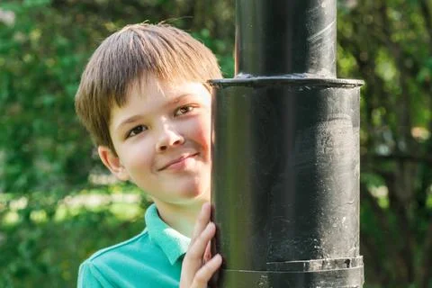 8-year-old boy with dark hair stands behind a metal lamppost. Cute brunet boy Stock Photos