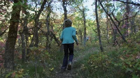 8 year old boy jogs along forest path to catch up to mother slow motion 스톡 동영상 194449284