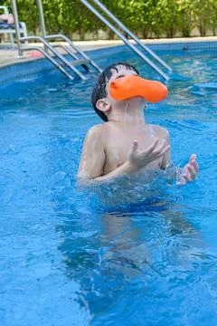 8 year old boy in the pool getting hit in the face by a water bomb. Stock Photos