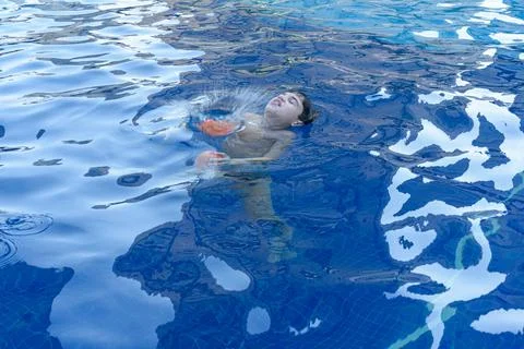 8 year old boy in the pool being covered by water from a water bomb. Stock Photos