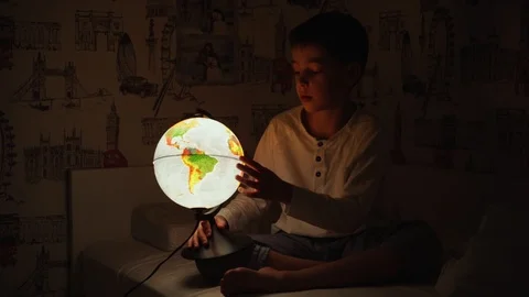 8 year old boy sitting in bed at night rotating the globe and dreams of Stock Footage 101028071